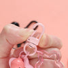 A hand holds a pink star charm pendant keychain against a light pink background.