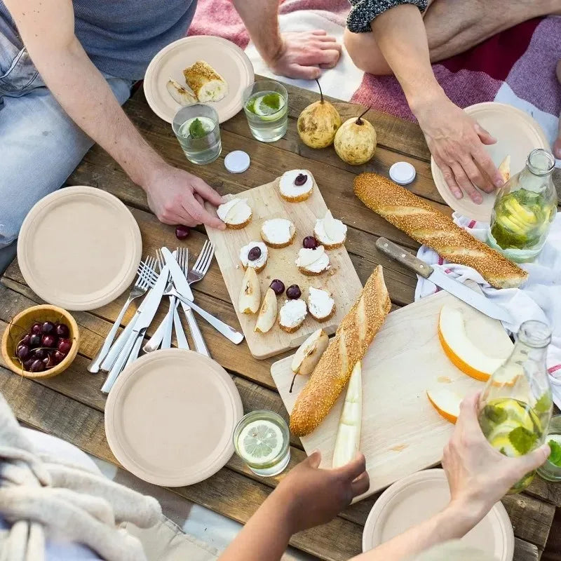 Hands are serving food from disposable paper plates on a wooden table.