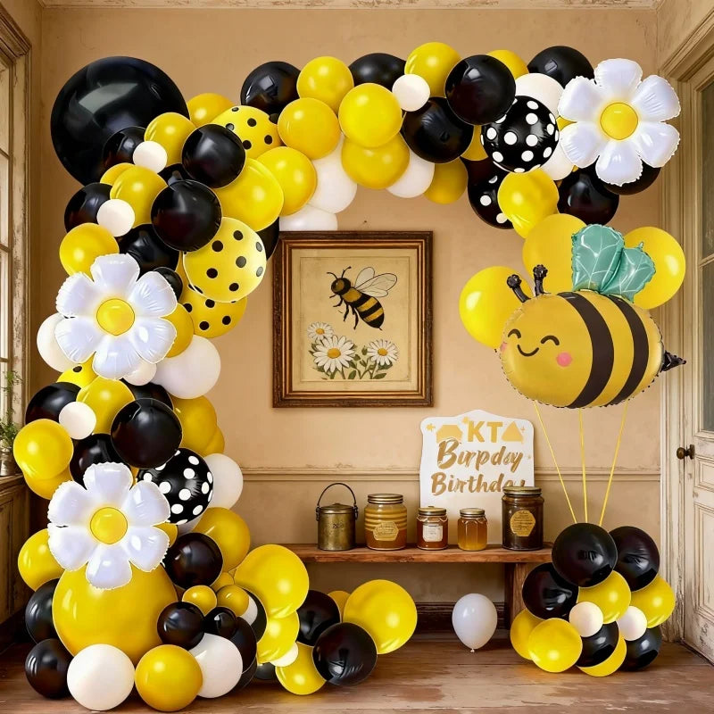 A yellow and black balloon arch set featuring bees and daisies against a light background.