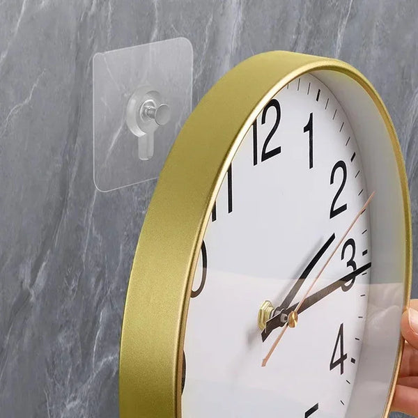 A round gold-rimmed clock with a white face and black numbers is mounted on a gray marble wall.