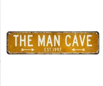 A rectangular, weathered yellow metal street sign with the text THE MAN CAVE EST. 1997.