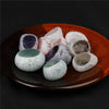 A collection of tumbled natural crystals including clear quartz, rose quartz, and amethyst on an orange dish.