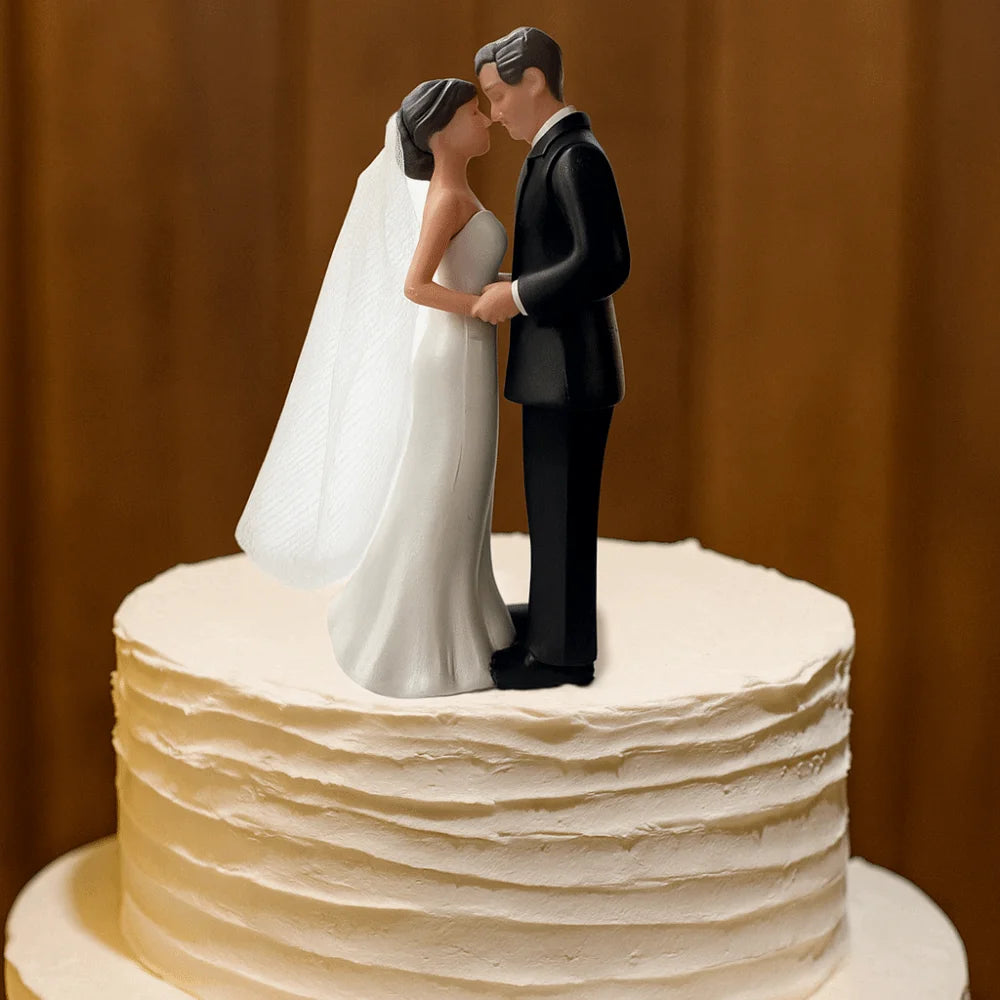 A wedding cake topper featuring a bride and groom figurine embracing.