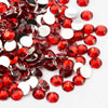 A close-up view of round flatback resin rhinestones in red and clear colors scattered on a white background.