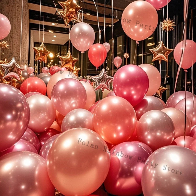 A close-up of pink and gold latex balloons hanging in a party decoration display.