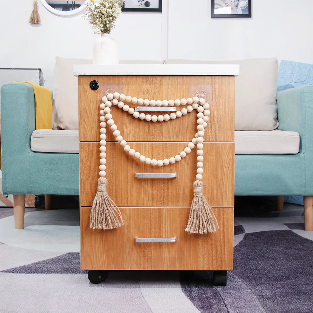 A wooden cabinet with glass doors featuring beaded tassels used as a wall hanging in a light-colored room.
