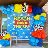 A colorful balloon arch featuring blue, yellow, and red latex balloons with cloud and cow print patterns for party decor.