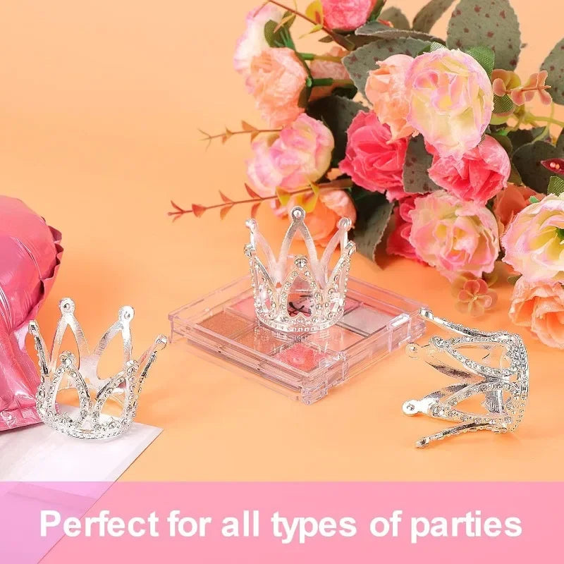 Silver glitter crown cake toppers and decorations displayed next to pink roses on an orange background