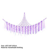 A purple handmade knitted storage hammock for toys and plushies with dangling strands.