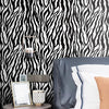 A close-up of a bedroom wall covered in black and white zebra print wallpaper.