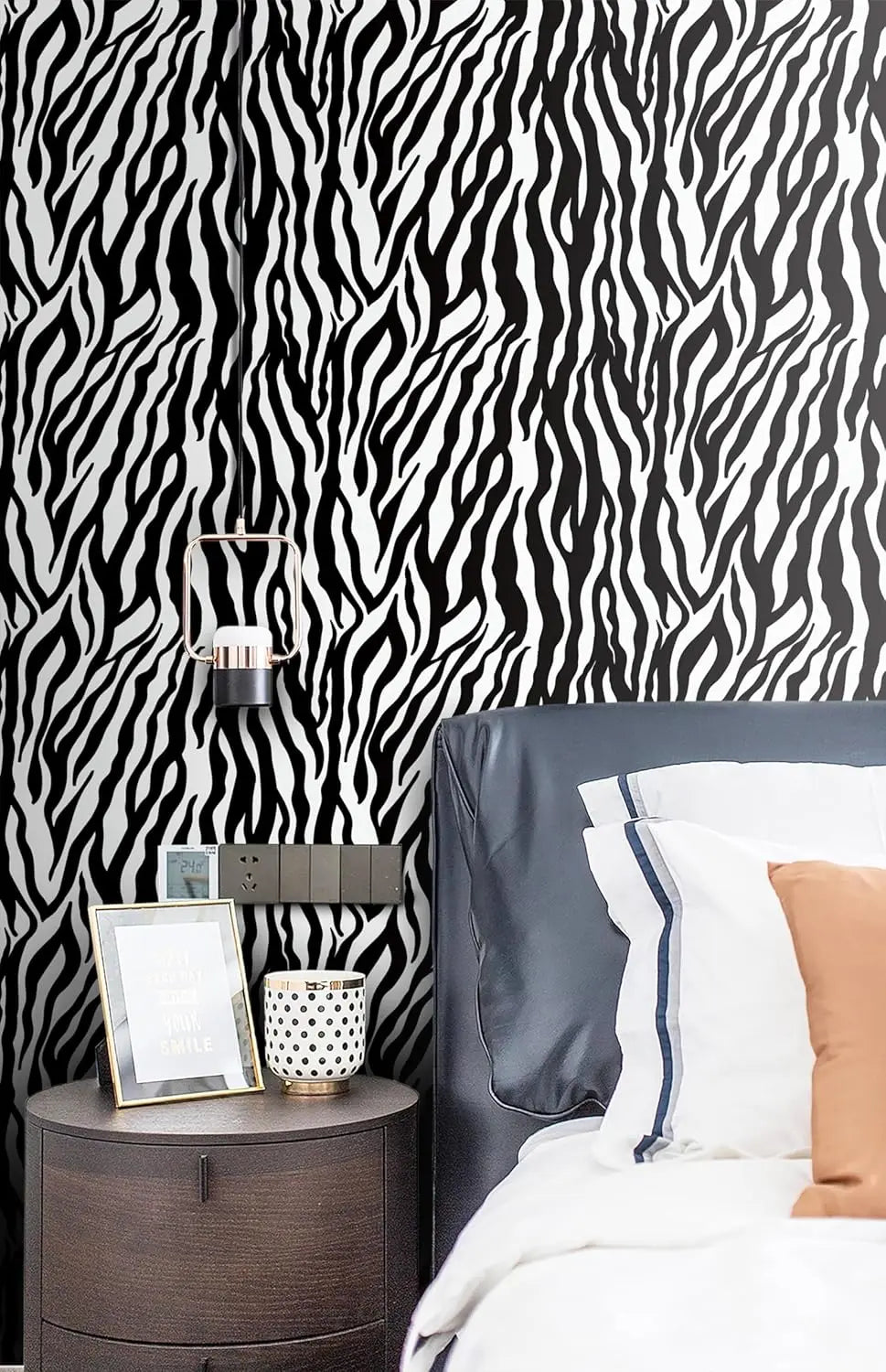 A close-up of a bedroom wall covered in black and white zebra print wallpaper.