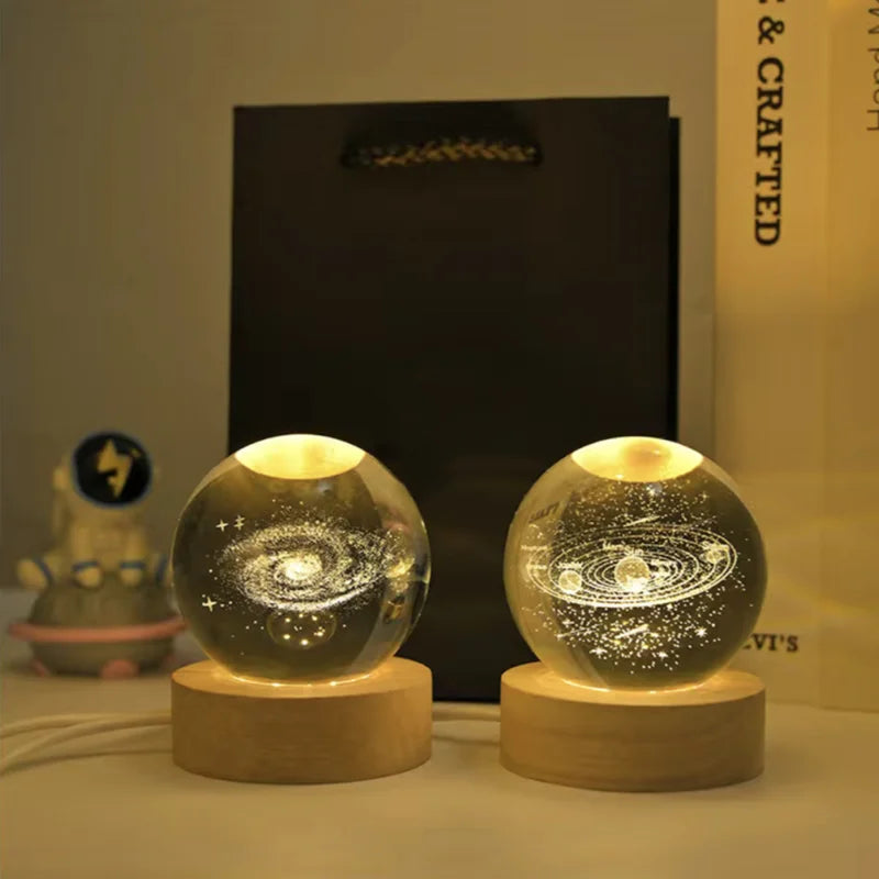 A glass crystal ball night light with a swirling galaxy design rests on a wooden base.