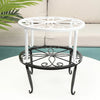 A decorative black and white metal plant stand with a circular saucer, shown on a white table.