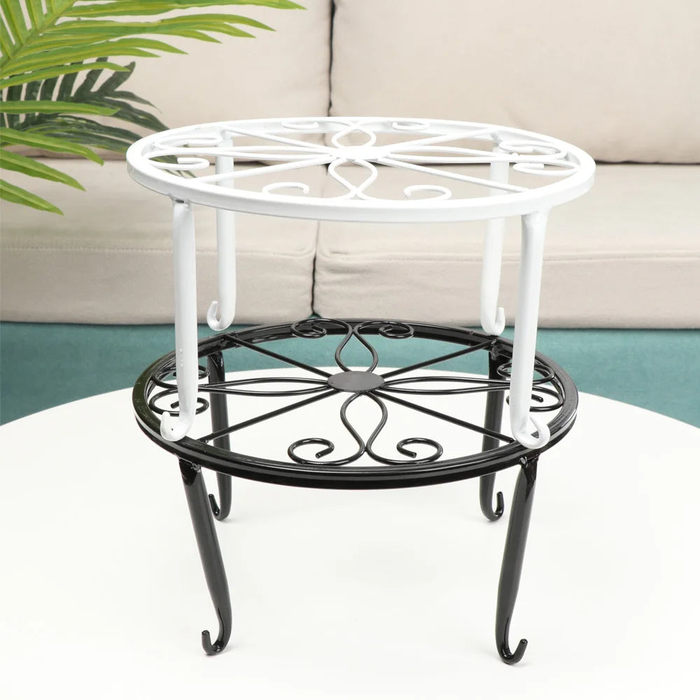 A decorative black and white metal plant stand with a circular saucer, shown on a white table.