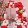 A pink and red balloon arch wreath featuring strawberries and foil accents.