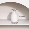 A white ceramic vase is displayed on a shelf, showing its dimensions.