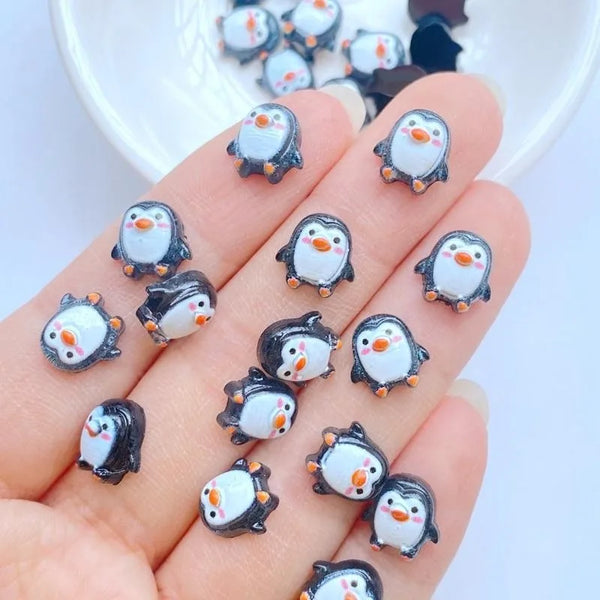 A hand holds a collection of small resin penguin figurines in various poses and colors.