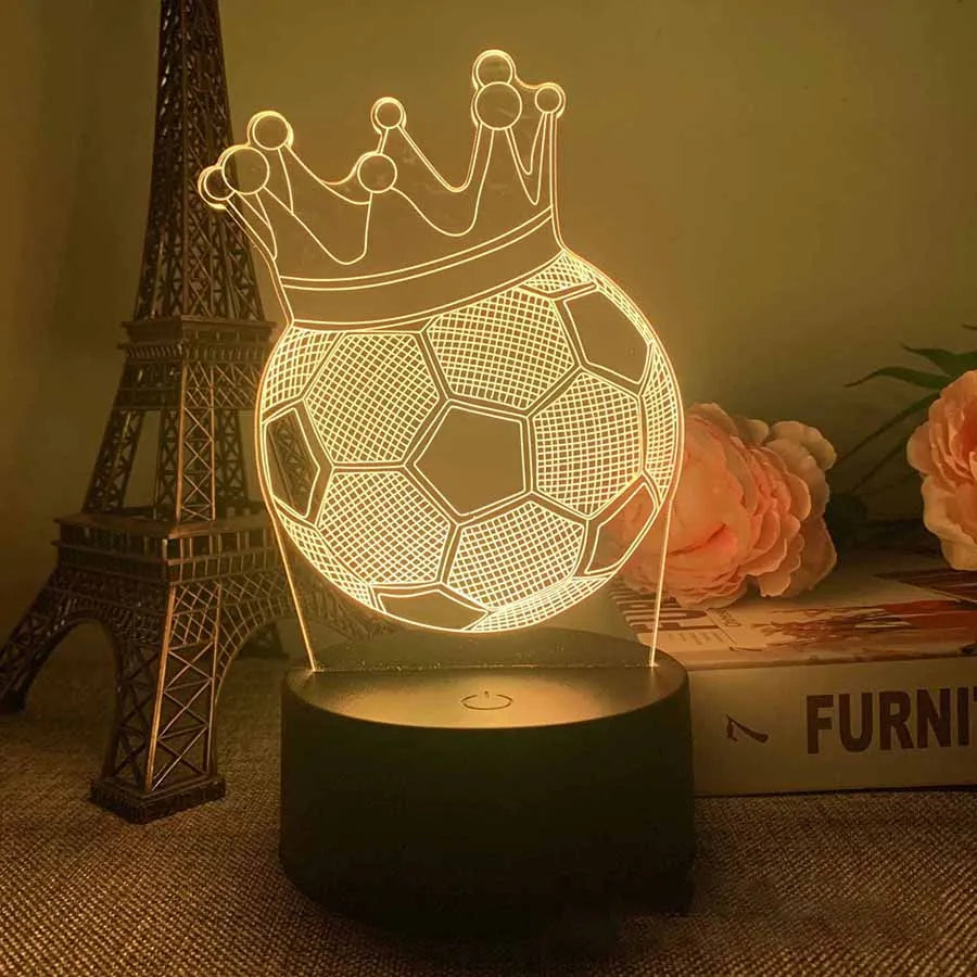 A glowing wireframe football crown night light rests on a dark base next to an Eiffel Tower model.