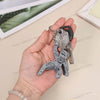 A hand holds a set of collectible figurines featuring Rocky and Grace, including a key.