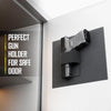 A black gun holder is mounted on a white wall, designed for a safe door.