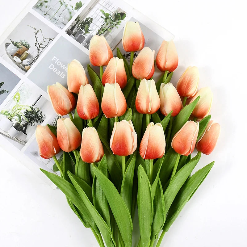 A bouquet of lifelike artificial tulips in shades of peach and orange on green stems.