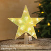 A sparkling, star-shaped LED Christmas tree topper with a warm white glow displayed on a surface.