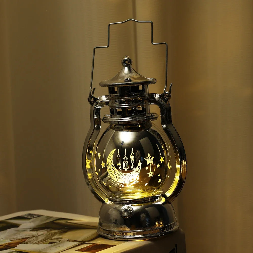 A silver LED lantern night light with a decorative lid and star patterns, emitting a warm glow.