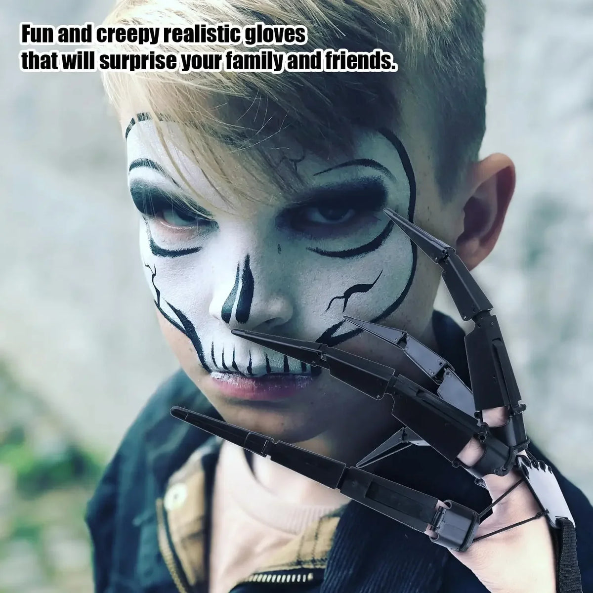 A young boy wearing realistic white and black clown makeup and articulated skeleton hand gloves.