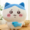 A white and blue Usagi Chiikawa plush doll with pink accents sitting on a wooden surface.