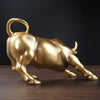 A golden sculpture of a bull in profile on a dark wooden surface.