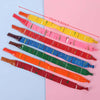 A collection of colorful rocket balloon strips in various shades of red, pink, yellow, and green laid out on a light pink bac