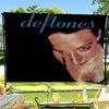 A black banner featuring a close-up portrait of the band Deftones, with green foliage in the background.
