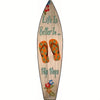 A wooden surfboard sign with the text Life Is Better In Flip Flops and floral decorations.