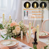 A set of six flimmering LED taper candles displayed on a table setting with flowers and tableware.