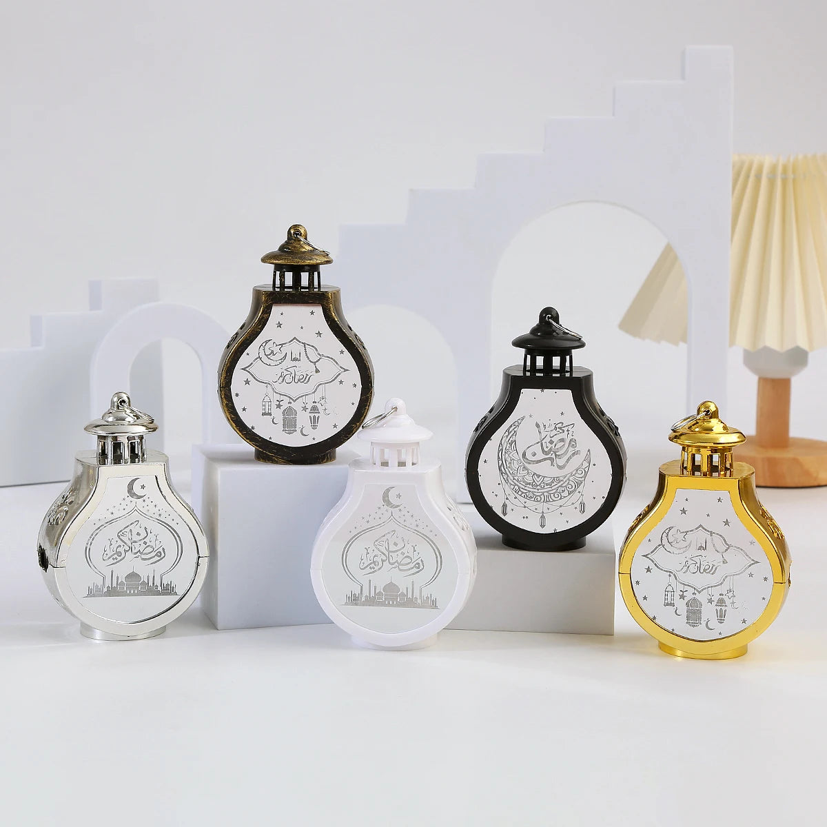 A collection of elegant LED star and moon lanterns in gold, silver, and black on a white surface.