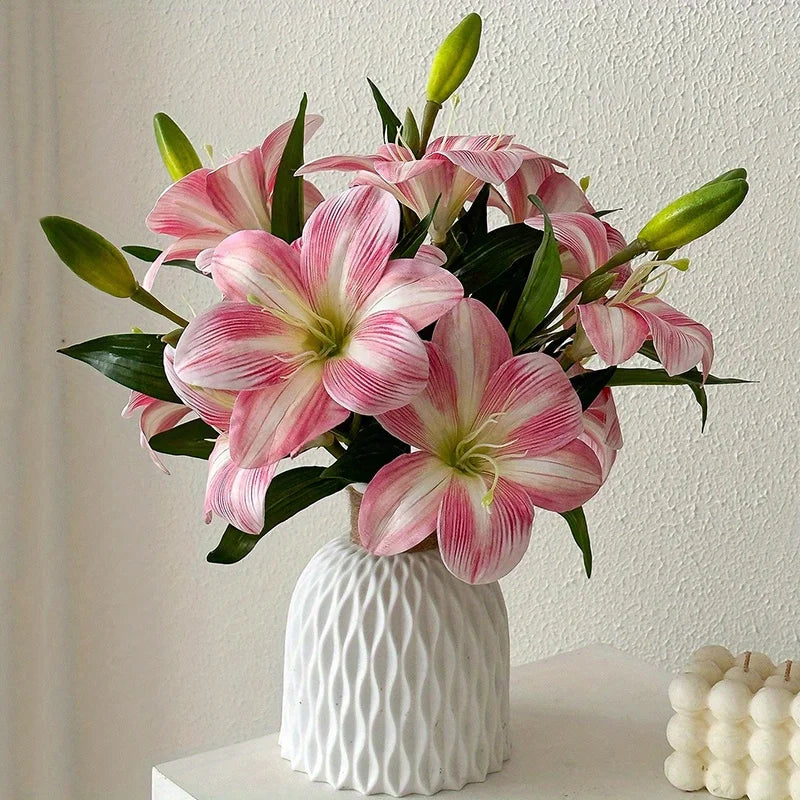 A bouquet of pink and white artificial lilies with green buds in a white textured vase.