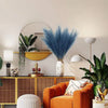 A vibrant orange armchair sits in a modern living space decorated with natural textures and gold accents.