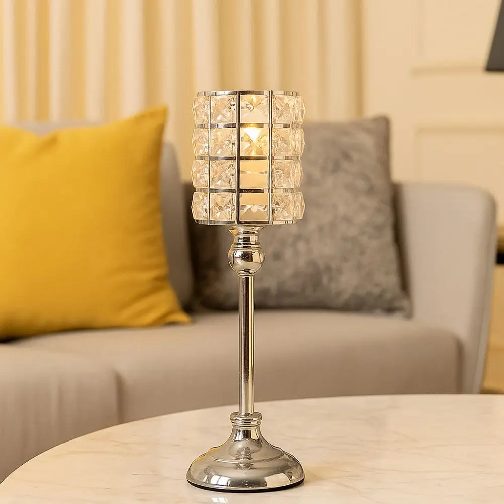 Un candelabro de cristal transparente con pantalla facetada sobre una mesa de mármol.