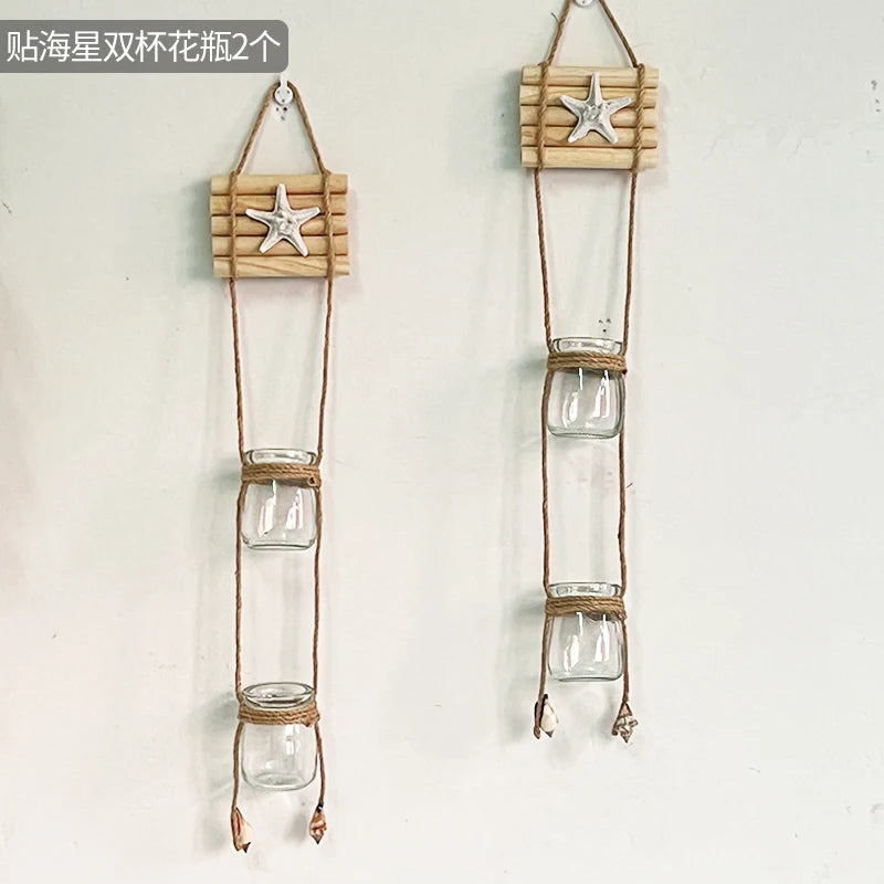 A wooden hanger displaying a starfish decoration and three glass terrariums suspended by twine.