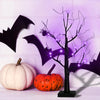 A glowing Halloween birch tree with purple LED lights stands next to a white pumpkin and an orange pumpkin.