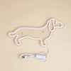 A white neon sign shaped like a dog outline is shown with its USB power cord.