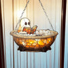 A glass hanging decoration featuring a ghost figure reading an open book submerged in glowing amber liquid.
