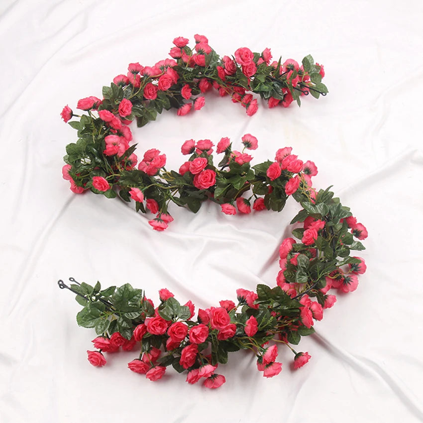 A garland of pink and red silk roses on a green vine used for wedding or home decor.
