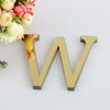 A gold 3D letter W made of mirror material is displayed next to a bouquet of pink and cream flowers.