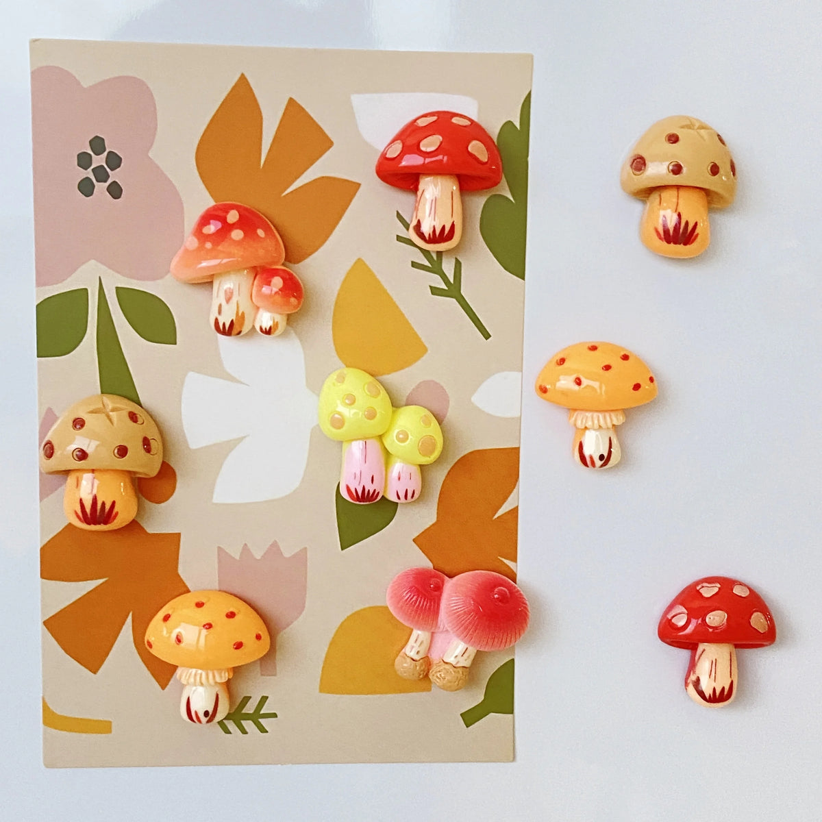 A set of nine colorful, cute decorative mushroom fridge magnets on a light beige card.