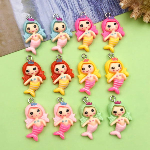 A collection of pink and yellow resin mermaid princess charms for jewelry making