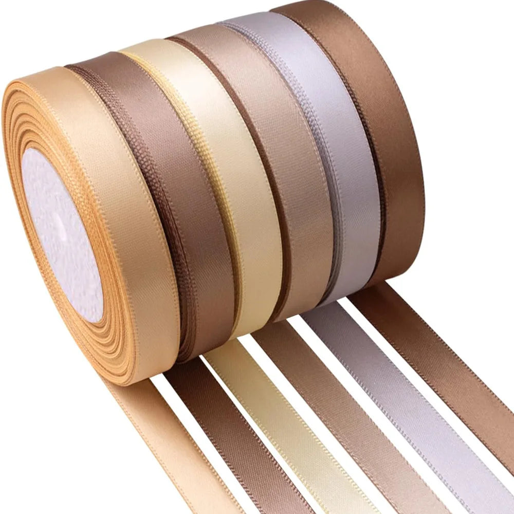 A roll of satin silk ribbon in various shades of beige and gold, with several strips unwound.