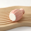 A pink ceramic mini vase resting on a light wooden surface.