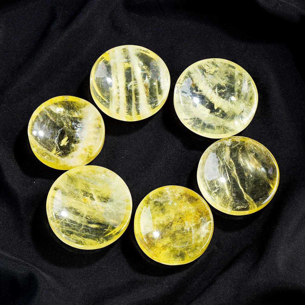Nine polished yellow citrine crystals arranged in a circle on a black background