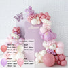 A pink and white balloon garland kit featuring various sized balloons arranged in a floral design against a light pink backgr